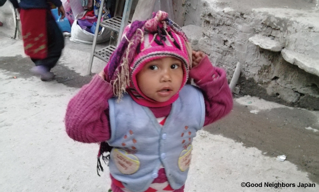 額にたすき掛けをしてかごを背負う子ども