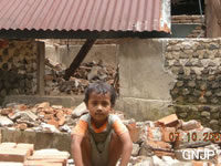 地震により倒壊した家の前に立つイチャンと家族