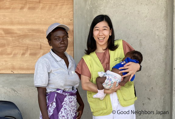 建設したヘルスセンター前で赤ちゃんを抱くグッドネーバーズ・ジャパンのスタッフ